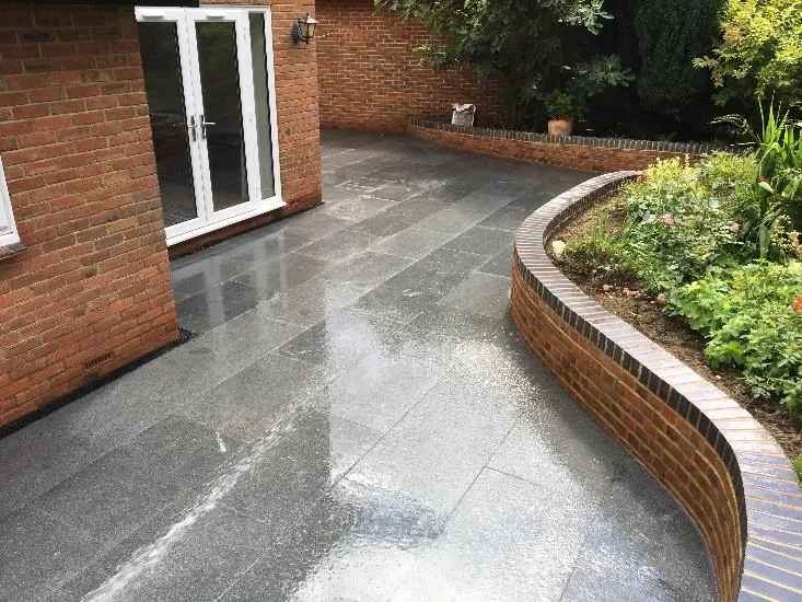 Curved brick planter wrapping a granite patio in Sevenoaks